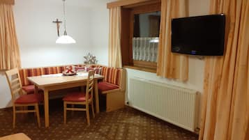 A dining area with a table, chairs, and a television mounted on the wall.