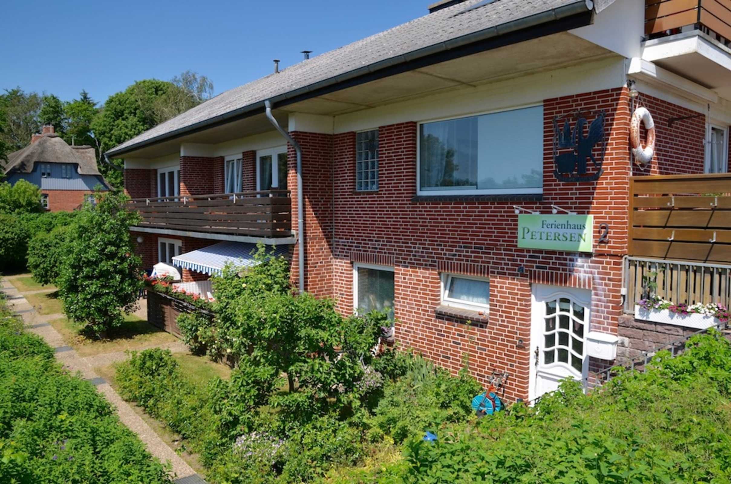 A two-story brick building with a sign reading "Ferienhaus PETERSEN 2".