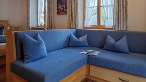 A room with a blue sofa, wooden ceiling, and a window with curtains.