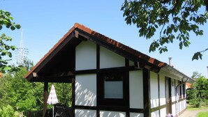 A small, single-story building with a sloped roof and a covered porch area. - Vacation home 175 Mohikaner 40qm up to 5 persons with pet - Ferienhaus Mohikaner (Hollern-Twielenfleth)