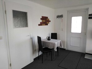 Une pièce comprenant une table à manger, des chaises, une fenêtre et une porte.