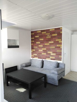 Un salon moderne avec un canapé gris, une table basse noire et un mur d’accent orné d’un motif en briques.