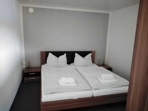 A double bed with two pillows and two folded towels.