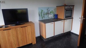 Una pequeña cocina equipada con televisor, cafetera y horno.