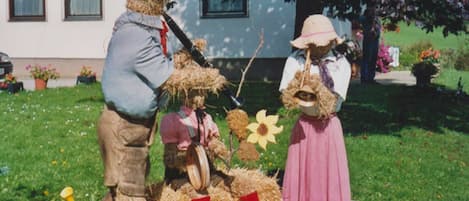 A person in a straw hat and a figure in a straw costume with a flower.