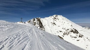 Pendiente nevada de una montaña con una estructura cruciforme a lo lejos.