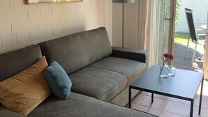 Ein modernes Wohnzimmer mit einem grauen Sofa, einem kleinen schwarzen Tisch und einer Stehlampe.