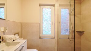 Un bany modern amb una cabina de dutxa de vidre, un vàter i un lavabo amb mirall.