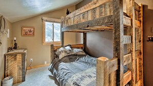 A bunk bed with a rustic wooden design, a small bedside table, and a window with a view of trees. - Secluded mountain retreat (Dolores)