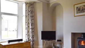 A living room with a fireplace, a television, and a wooden cabinet. - 3 bedroom accommodation in Skipton (Skipton)