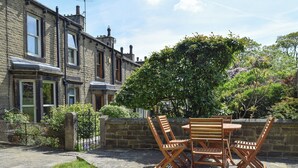A patio with a table and chairs, surrounded by stone walls and a garden. - 3 bedroom accommodation in Skipton (Skipton)