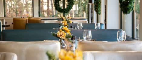 Ein Restaurant mit einem langen Tisch, gedeckt für das Essen, mit einem Blumengesteck und einem floralen Mittelstück.