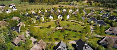 Un pueblo con casas tradicionales, un espacio verde central y un edificio con tejado de paja.