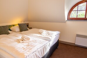 A hotel room with two beds, a window, and a radiator.