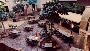 An indoor courtyard with multiple tables and chairs, surrounded by brick walls and stone flooring.