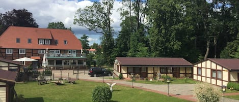 Un hôtel avec un toit rouge, un espace extérieur aménagé et couvert, et une pelouse bien entretenue.