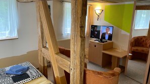 A room with a wooden ladder, a television, a sofa, and a chair. - 08 DZ - Island-Hotel Dobbertin (Dobbertin)
