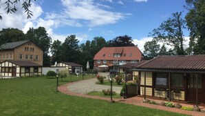 A residential area with multiple houses, a paved courtyard, and a large building with a red roof. - 08 DZ - Island-Hotel Dobbertin (Dobbertin)