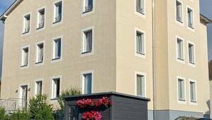 Un edificio de varios pisos con fachada color beige, múltiples ventanas y balcones.