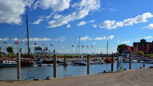 Un puerto deportivo con varias embarcaciones amarradas, cielo despejado y un edificio al fondo.