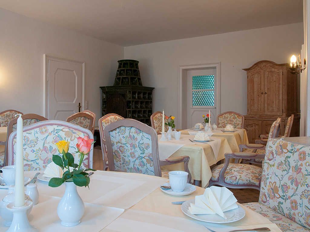 Ein Essbereich mit stuhlförmigen Sitzgelegenheiten mit Blumenmuster, weißen Tischdekorationen und einem Möbelkorpus im Vintage-Stil.