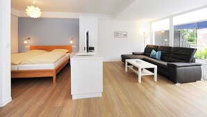 A modern room with a bed, a sofa, a coffee table, and a TV. - Vacation apartment Leuchtturm - Haus Kunterbunt (Esens)