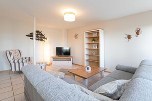 A modern living room with a sofa, a coffee table, a TV, and decorative items on the wall.