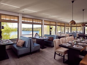 A restaurant with a lakeside view, featuring a mix of seating including a booth and a table with chairs. - 95m² holiday home - holiday homes on the lake (Nossentiner Hütte)