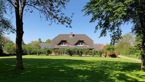 A house with a sloped roof, surrounded by a well-maintained lawn and trees.