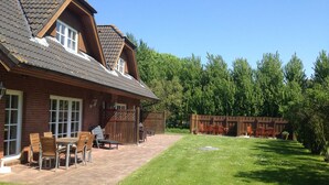 A house with a patio area, a wooden deck, and a well-maintained lawn.