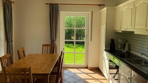 A kitchen with white cabinets, a black countertop, and a window with a view of a green garden.
