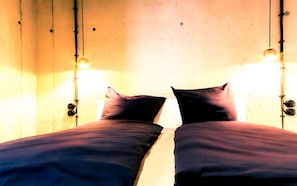 A bed with two pillows and a hanging light fixture above it. - The Edged (06) - Z1-THE HOUSE (Zwenkau)