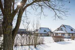 Ein mit Schnee bedecktes Haus mit geneigtem Dach und einem sichtbaren Schornstein.