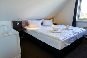 Ein Hotelzimmer mit Bett, Nachttisch, Lampe und Fenster.
