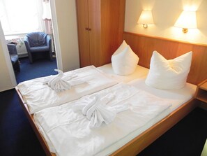 Une chambre d’hôtel avec un lit bien fait, deux oreillers et une chaise.