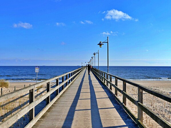 A wooden boardwalk extending towards the ocean with a clear sky.