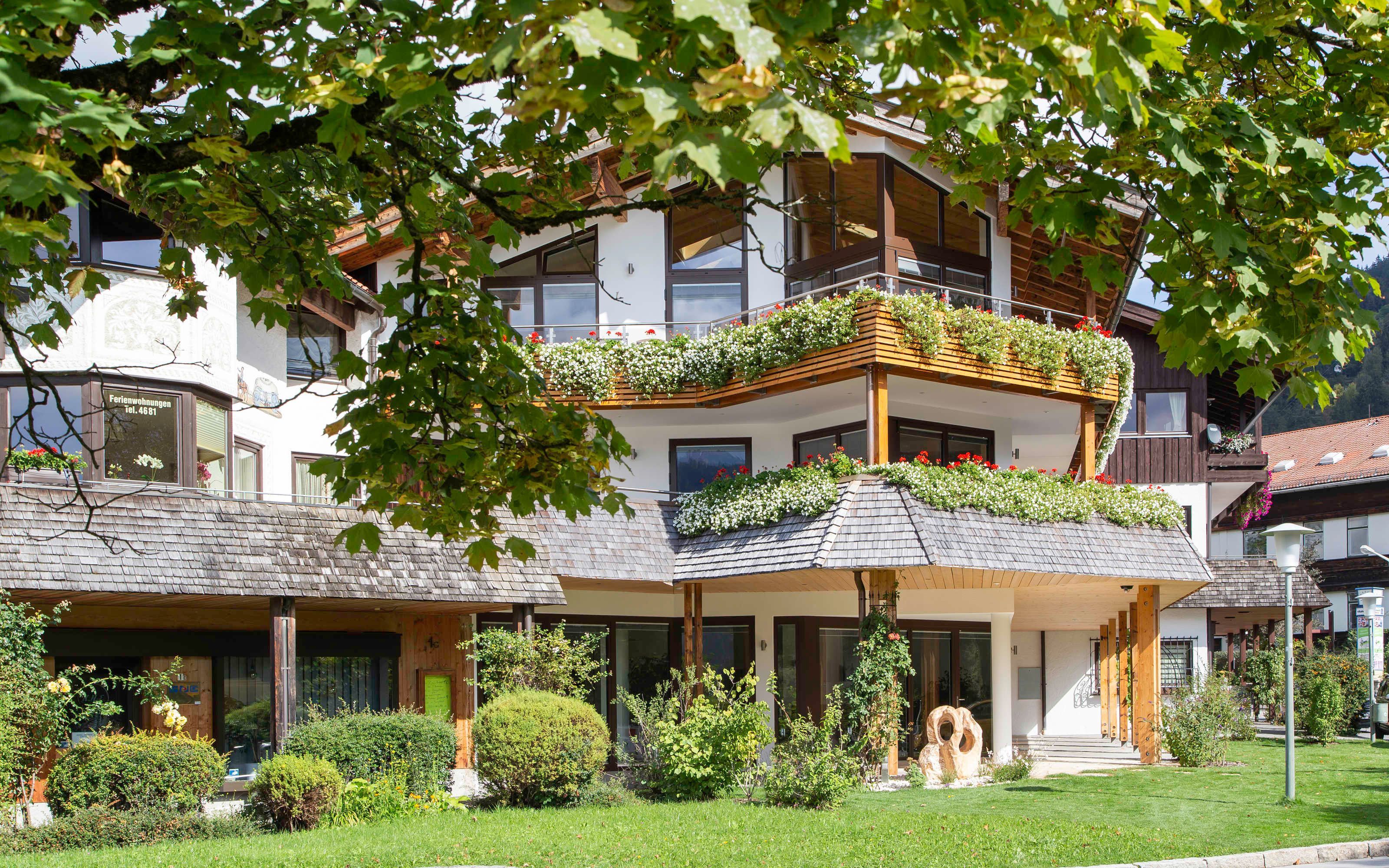 Een meerlaags gebouw met balkons, een groen gazon en een kleine entree met een houten deur.