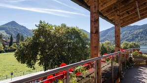 Ein Holzbalkon mit Metallgeländer, der auf eine Berglandschaft mit einem See blickt.