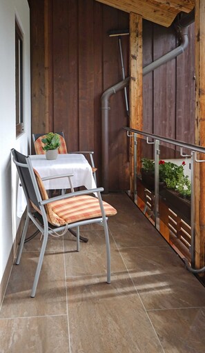 Eine Terrasse mit Tisch, Stühlen, einer Topfpflanze und einem Blumenkasten.