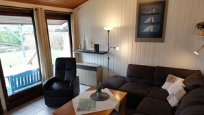 Een woonkamer met een bank, een stoel, een tafel met een kaart, een lamp en een lijst met een afbeelding aan de muur.