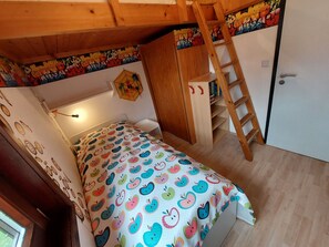A small, cozy bedroom with a bed, a ladder, and a wardrobe.