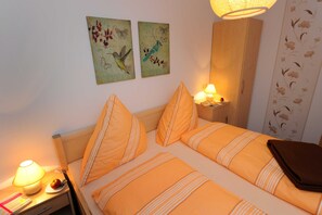 Ett hotellrum med två sängar, ett nattduksbord med en lampa och konst på väggen.