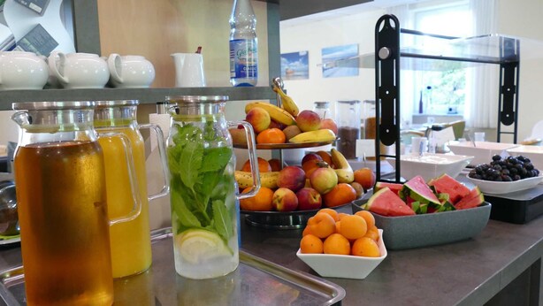 A breakfast buffet with various fruits, beverages, and a fruit display.