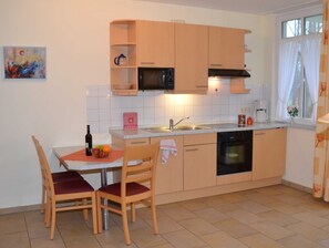 A compact kitchen with a dining table, chairs, a microwave, a sink, and a dishwasher.