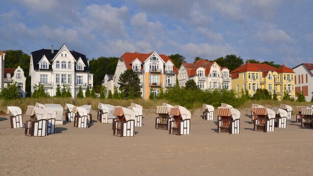 Una hilera de cabañas de playa con un conjunto de casas coloridas al fondo.
