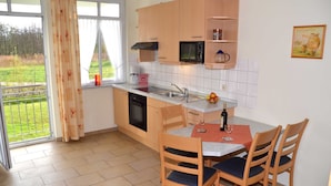 Una cocina con ventana, microondas, lavamanos y una mesa de comedor con sillas.