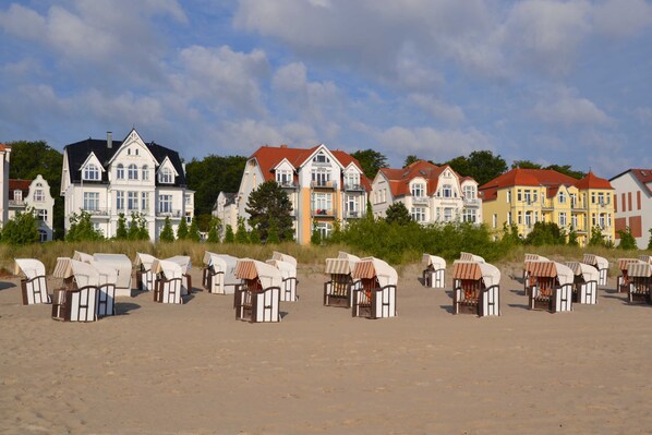 A row of beach huts with a row of colorful houses in the background.
