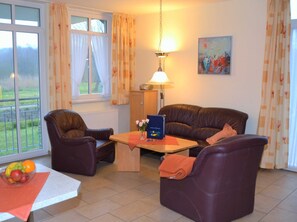 A living room with a sofa, two armchairs, a coffee table, and a lamp.