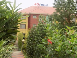 Stroll along the pathway to the entrance of the 4Ds Motel, surrounded by lush greenery.