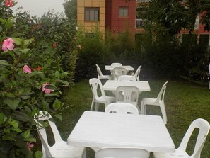 Relax in a serene garden setting with comfortable seating and lush greenery.